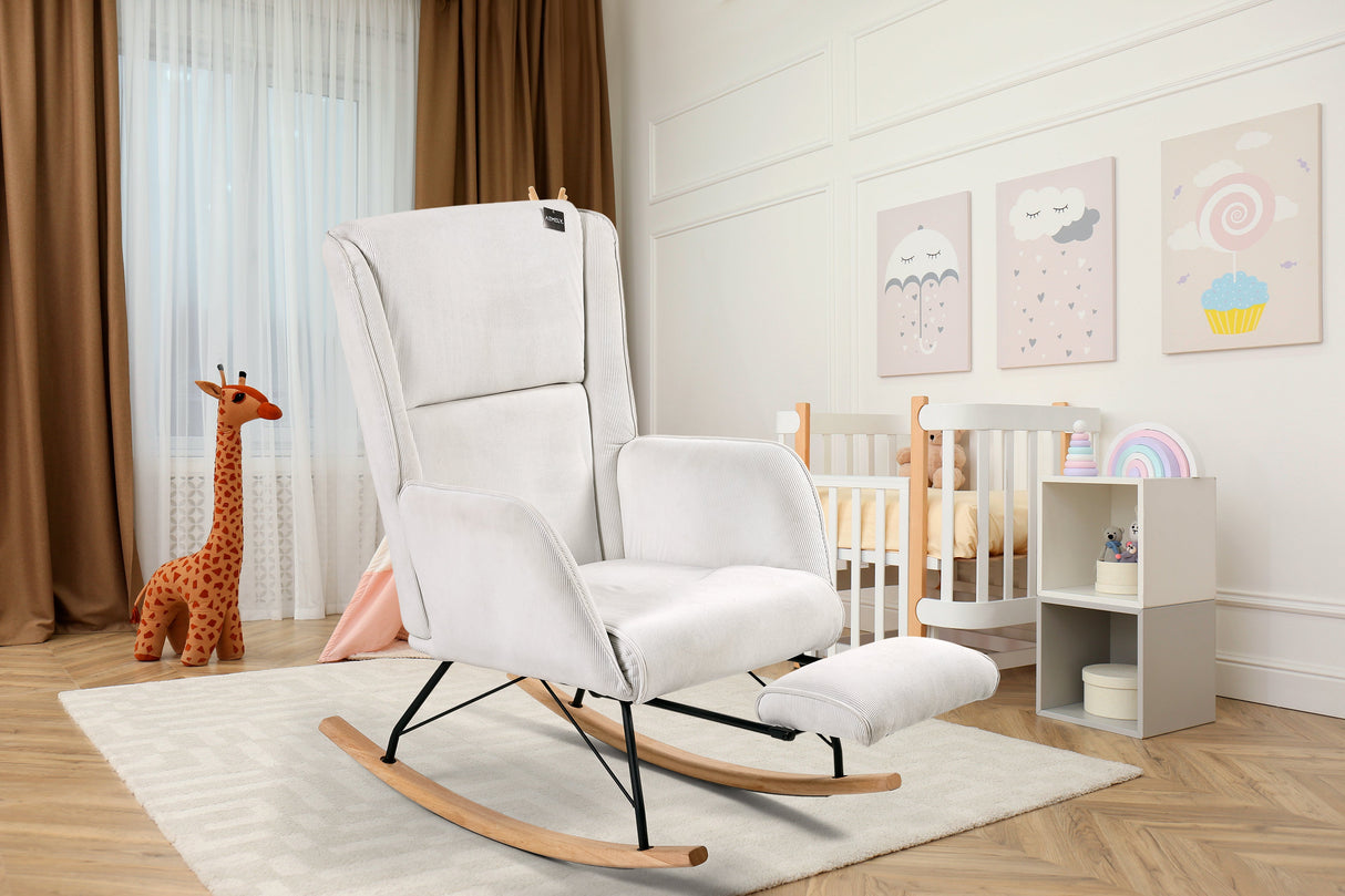 Aemely® Schommelstoel 'Relax' in wit ribstof met ingebouwde voetsteun, geplaatst in een kamer met een houten vloer en een gezellige inrichting.