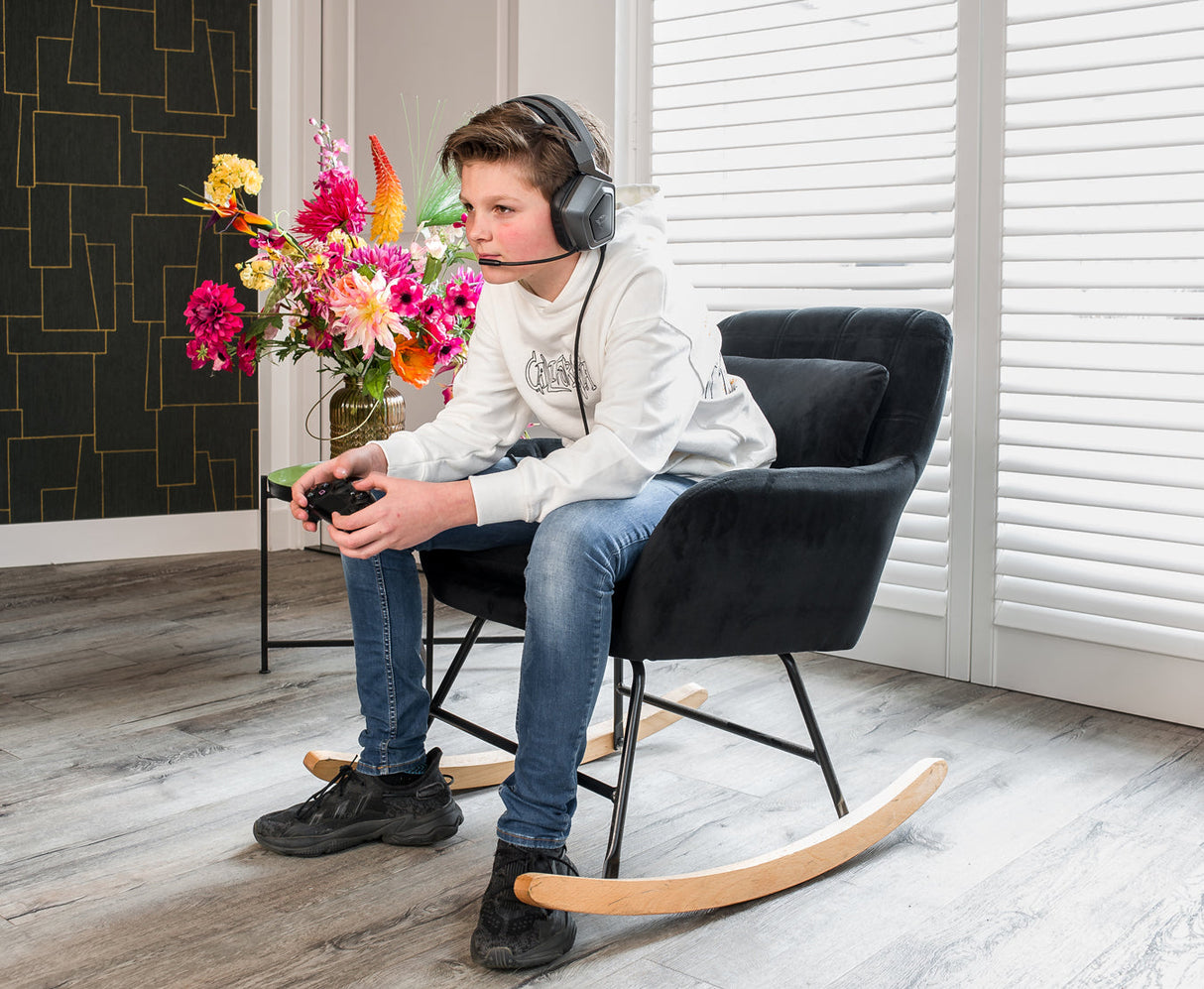 Jongen in de Aemely® Schommelstoel 'Sofie' – Zwart Velvet, zittend met koptelefoon, compacte fluwelen stoel ideaal voor woon- of babykamer.