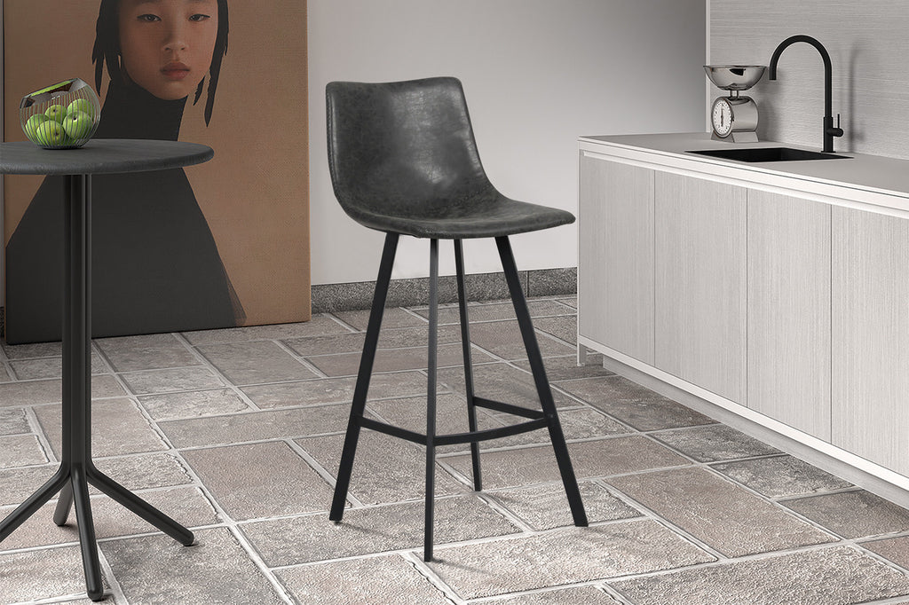 Barkruk 'Ozan' PU Zwart in een keuken, met zwart metalen onderstel en PU-leer zitting, naast een wit aanrecht en zwarte gootsteen.