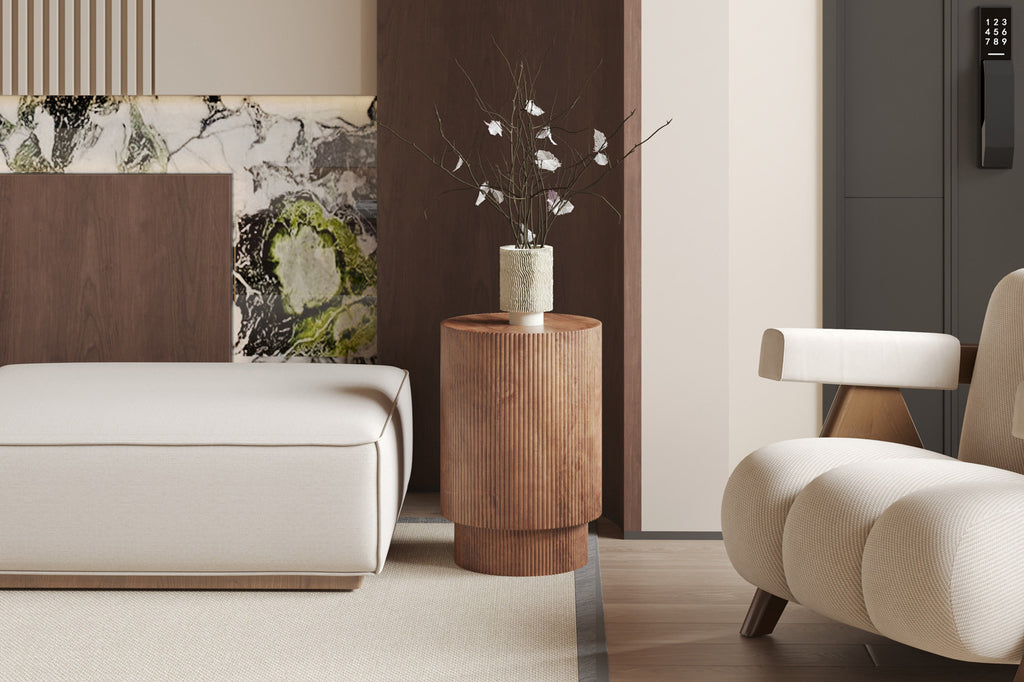 Bijzettafel 'Victor' van lichtbruin Mango hout, geplaatst op een houten vloer naast een witte bank en een vaas met bloemen.