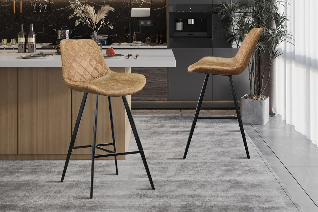 Barkruk 'Palmas' PU Cognac, twee bruine stoelen met zwarte poten in een keuken, naast een aanrecht en een plant.