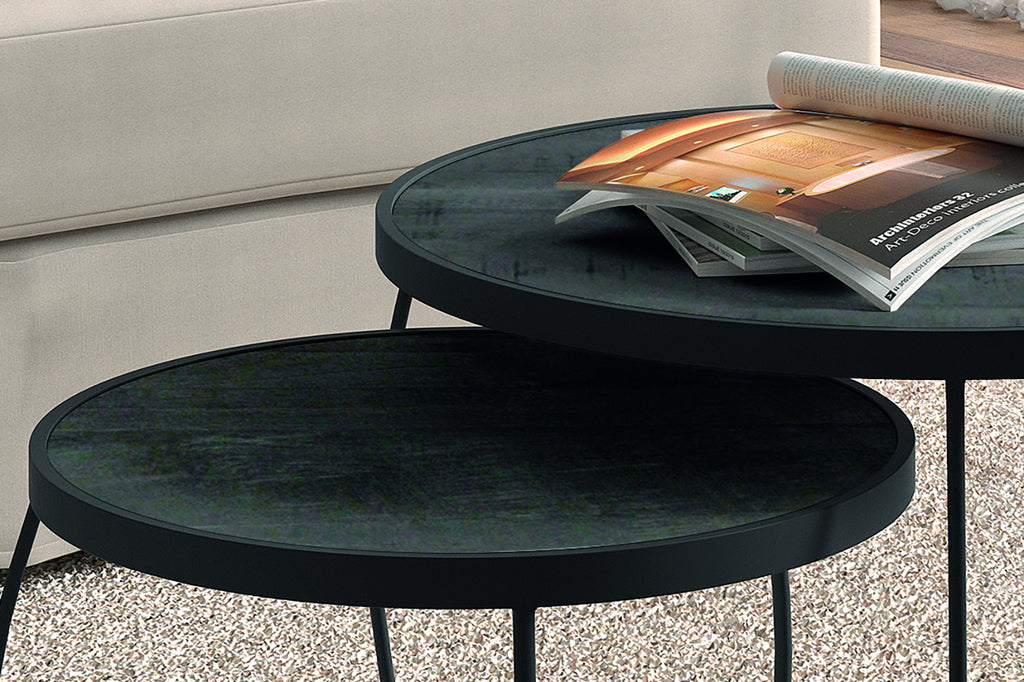 Salontafel 'Lars' 2-delig van Mango hout en zwart metaal, met een stapel tijdschriften erop, op een tafel in een huiselijke setting.