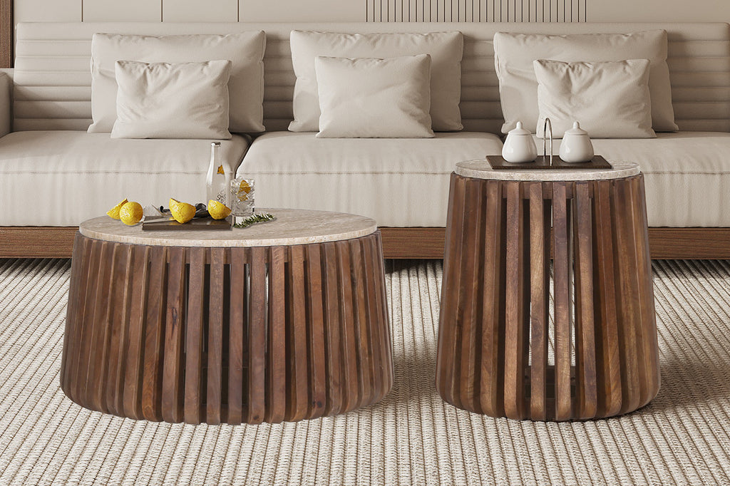 Salontafel 'Luuk' 70 cm rond, met mango houten frame en travertin blad, naast een witte bank met kussens en decoratieve voorwerpen op tafel.