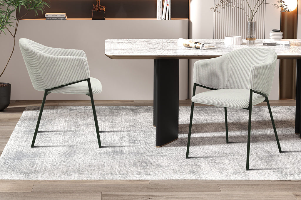 Stoel 'Hugo' Corduroy Lichtgrijs, twee witte stoelen met zwarte poten rond een tafel, met een boek en een vaas met plant erop.