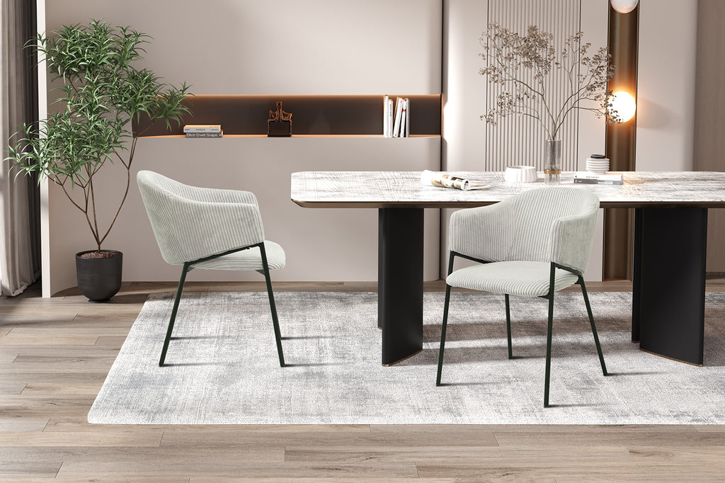 Stoel 'Hugo' Corduroy Lichtgrijs met zwarte poten, geplaatst bij een tafel en plant, perfect voor moderne interieurinrichting. Verpakt per twee.