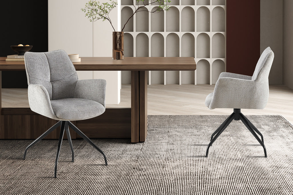 Stoel 'Lamor' draaibaar met grijze stof en zwarte metalen poten, geplaatst naast een tafel met vaas, passend in elke woonruimte.