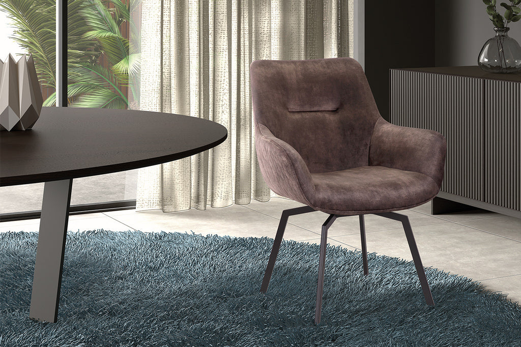 Stoel 'Modest' draaibaar in fluweel taupe, naast een tapijt met een tafel en vaas, perfect voor elke kamerinrichting.