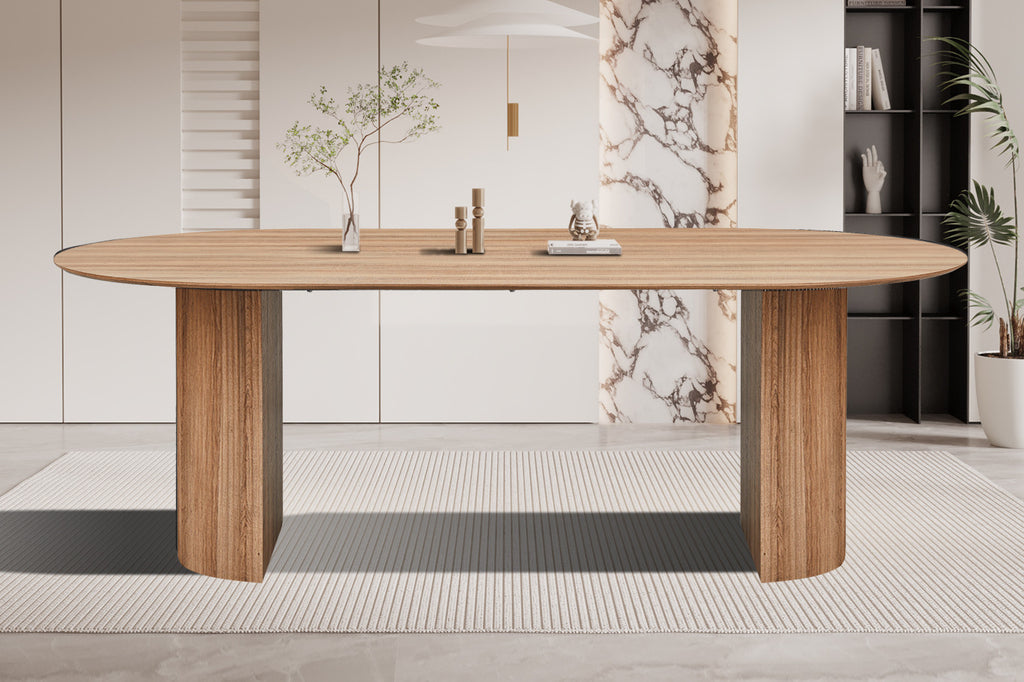 Tafel 'Lagos' 220 cm ovaal met een witte oppervlakte, geplaatst op een tapijt in een kamer, met een potplant en glazen vaas naast zich.