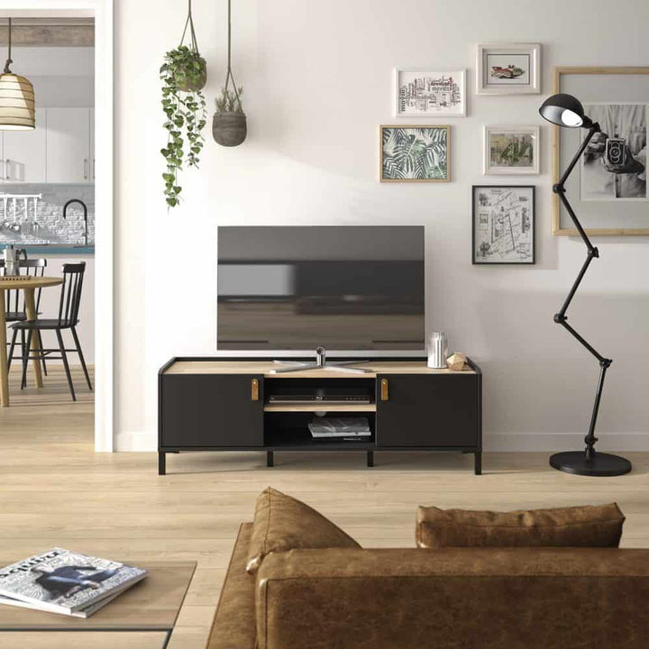 Amsterdam TV-kast 2-deurs 1 Plank in een moderne woonkamer met bank, tafels, en lamp; perfect voor industriële interieurs. Zwart/licht kastanje look, hout en staal.