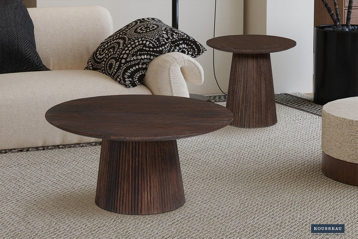 Salontafel 'Miguel' 50 cm Rond Mango Hout Donkerbruin, twee ronde houten tafels in een kamer, naast een witte bank op een tapijt.