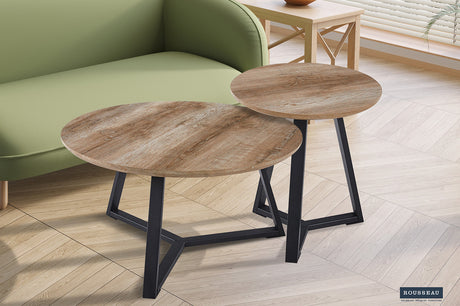Salontafel 'Paso 1' Decor Oude Eik, ronde houten tafel met zwarte poten, naast een groene bank, met MDF-blad en zandgevoel frame.