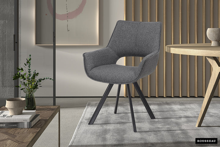 Stoel 'Tim' Stof Grijs met metalen poten en polyester bekleding, naast een vaas met plant, geplaatst in een minimalistisch ingerichte kamer.