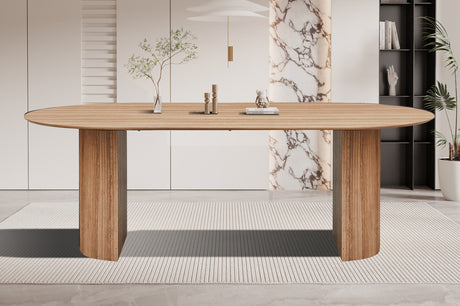 Tafel 'Lagos' 220 cm ovaal met een witte oppervlakte, geplaatst op een tapijt in een kamer, met een potplant en glazen vaas naast zich.