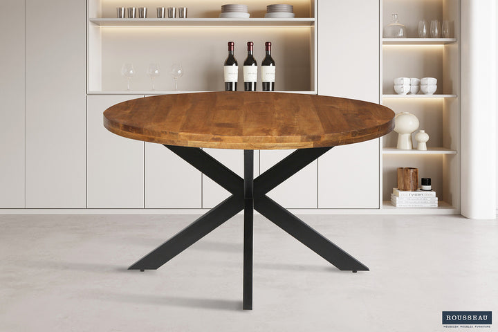 Ronde tafel 'Maria' van 130 cm met exotisch mangohouten blad en metalen structuur, gepresenteerd met wijnflessen op een houten oppervlak.